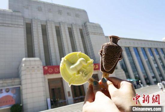 2021年7月30日，游客手拿“銅奔馬”“彩陶瓶”造型的雪糕，在甘肅省博物館前拍照打卡?！「哒?攝