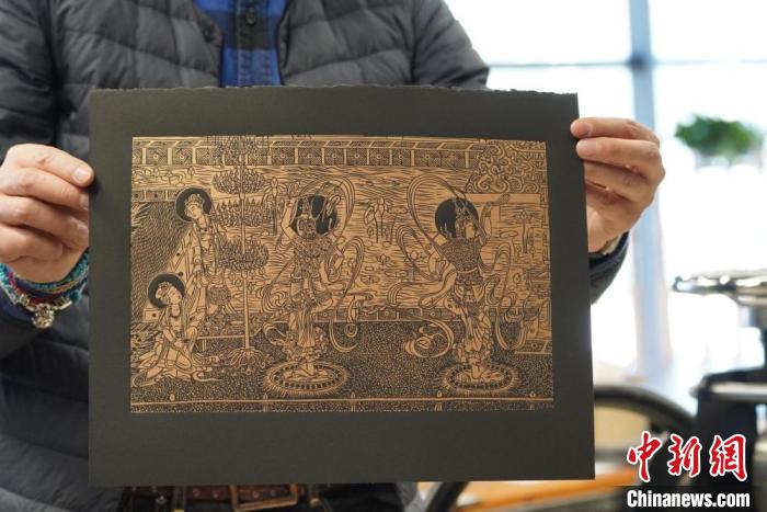 圖為手工書藝人展示敦煌雕版壁畫印刷品。　九美旦增 　攝