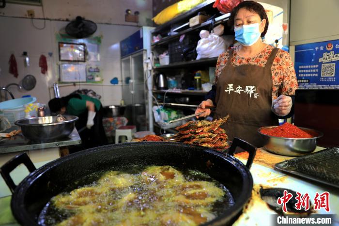 圖為平安驛·河湟民俗文化體驗地內(nèi)的商戶炸干板魚。　薛蒂 攝