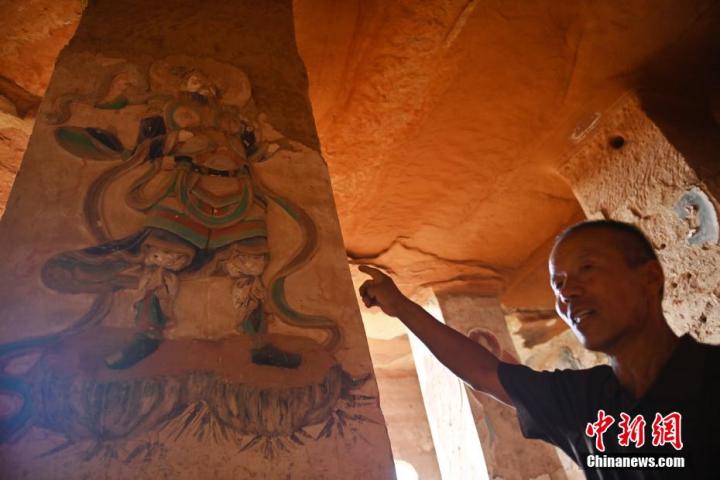 7月15日，甘肅省平?jīng)鍪袥艽h百里石窟長廊羅漢洞石窟內(nèi)，該窟文保員郭建平介紹窟內(nèi)石刻彩繪壁畫。郭建平家中三代人曾自發(fā)保護羅漢洞石窟。羅漢洞石窟遺存40余個窟龕，以北魏至清代風(fēng)格為主。中新社記者 李亞龍 攝</p>
<p>