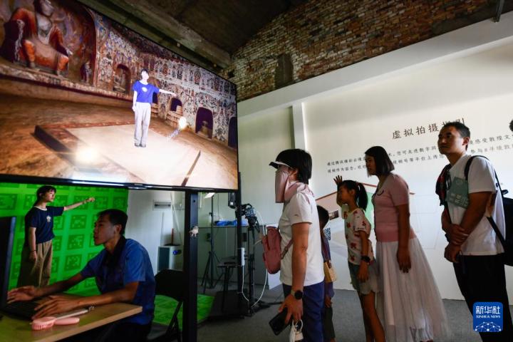 7月22日，游客體驗“尋境敦煌——數(shù)字敦煌沉浸展”后，在虛擬演播廳拍攝一段真人與洞窟虛擬場景交互的視頻。新華社記者 郎兵兵 攝</p>
<p>