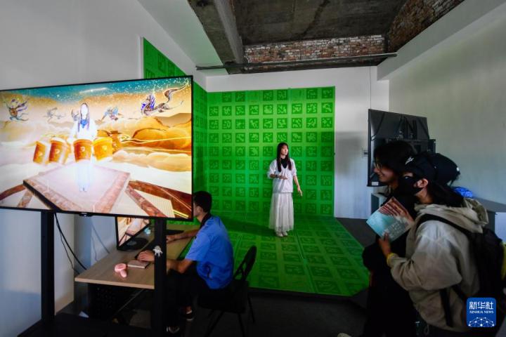 7月22日，游客體驗“尋境敦煌——數(shù)字敦煌沉浸展”后，在虛擬演播廳拍攝一段真人與洞窟虛擬場景交互的視頻。新華社記者 郎兵兵 攝</p>
<p>